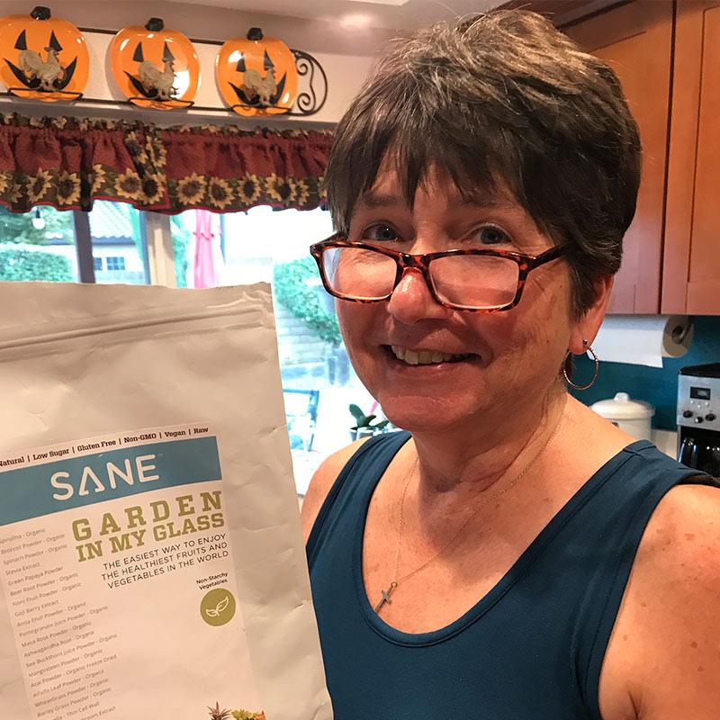 Smiling woman with glasses holding bag of product Garden In My Glass