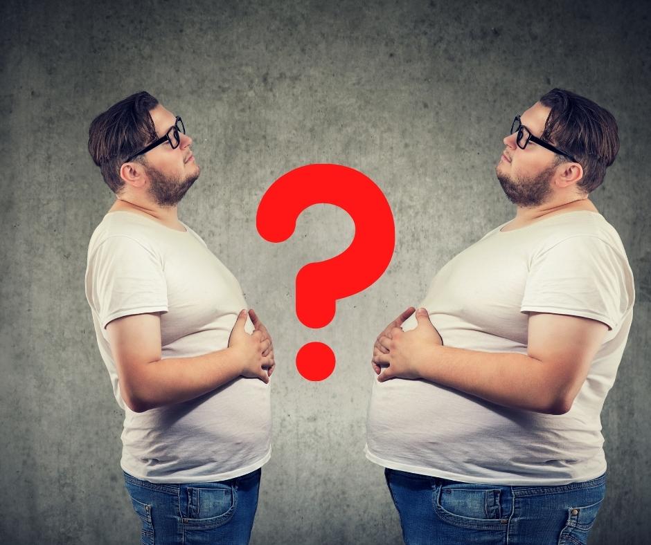 Am I Bloating or Fat? An image of a young chubby man looking at himself with a bloated stomach.